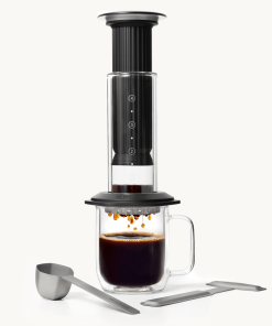 Aeropress Premium coffee maker in black with a glass mug of coffee