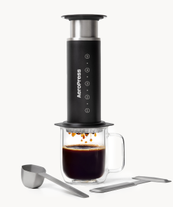Aeropress Coffee Maker Steel in black stainless steel with a glass mug of coffee