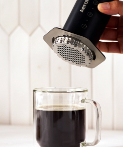 Hand pressing coffee with a black Aeropress Steel into a glass
