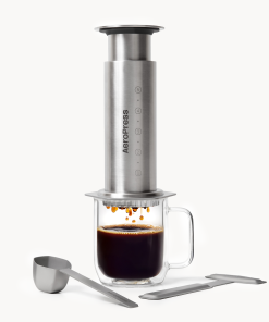 Aeropress Coffee Maker Steel in silver stainless steel with a glass mug of coffee