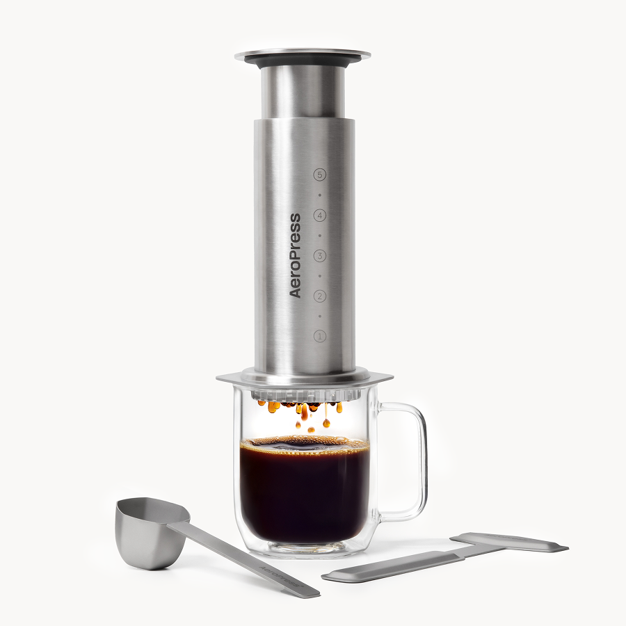 Aeropress Coffee Maker Steel in silver stainless steel with a glass mug of coffee