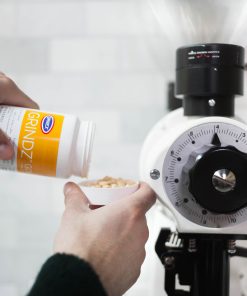Urnex Grindz tablets being added to a coffee grinder