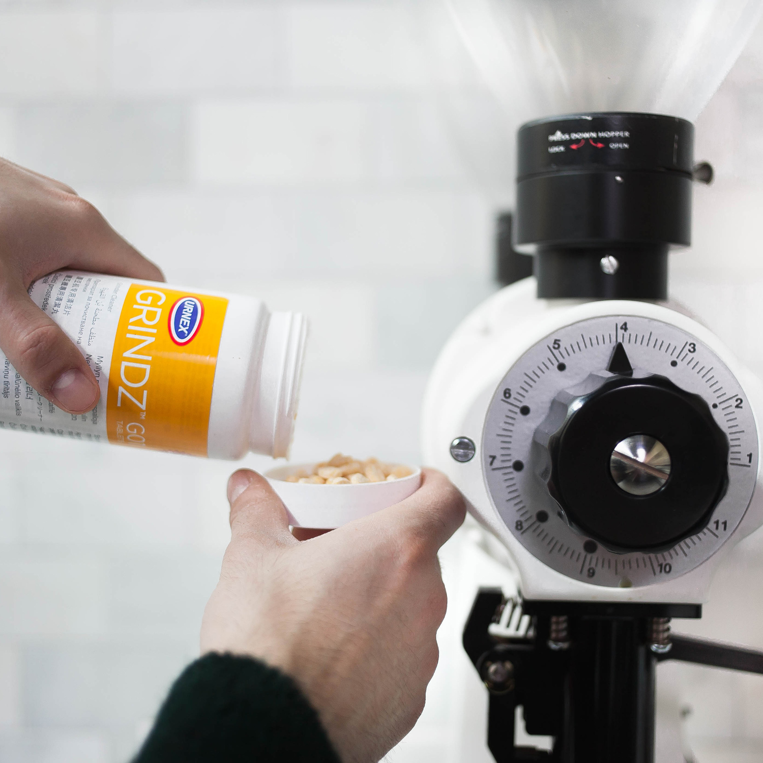 Urnex Grindz tablets being added to a coffee grinder
