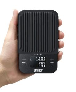 Wacaco Exagram compact coffee scale held in one hand to show its size